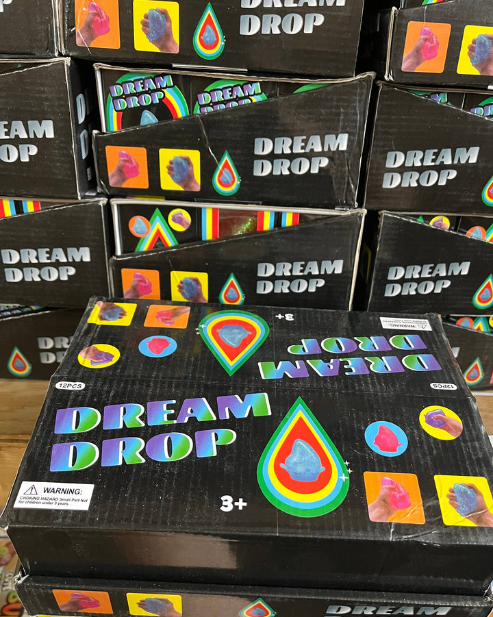 Multiple boxes of 'Dream Drop' with colorful graphics on a wooden surface.