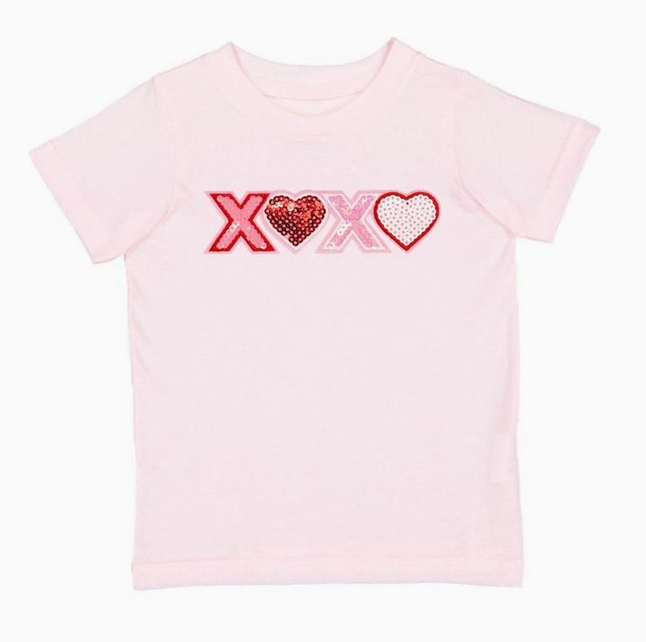 Pink t-shirt with 'XOXO' sequin design on a white background. Valentines day girls shirt