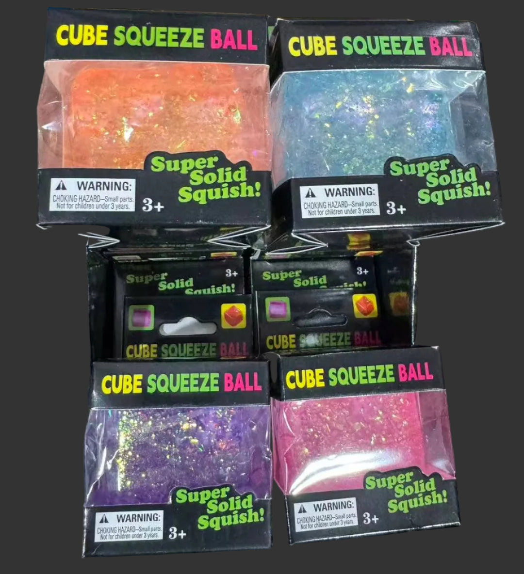 Multiple packages of Cube Squeeze Ball toys on a dark surface