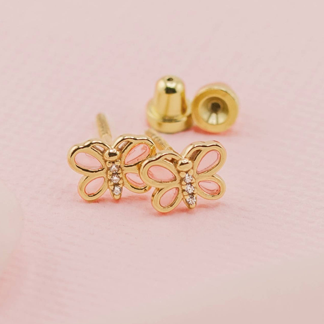 Gold butterfly earrings on a pink background