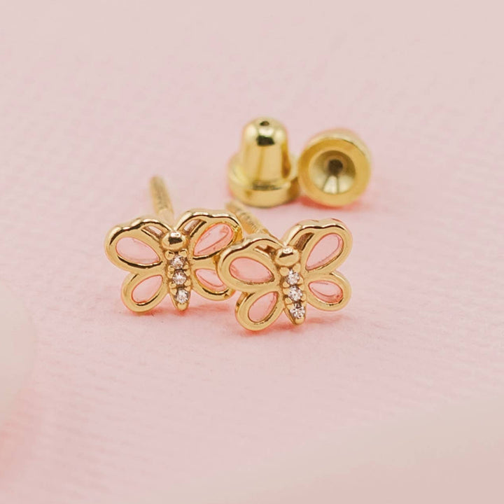 Gold butterfly earrings on a pink background