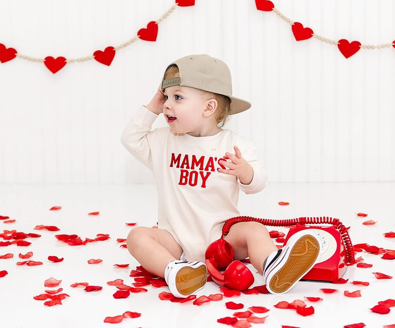 Child wearing a 'MAMA'S BOY' sweater bubble surrounded by red hearts and rose petals. Valentine's Day Boys Outfit