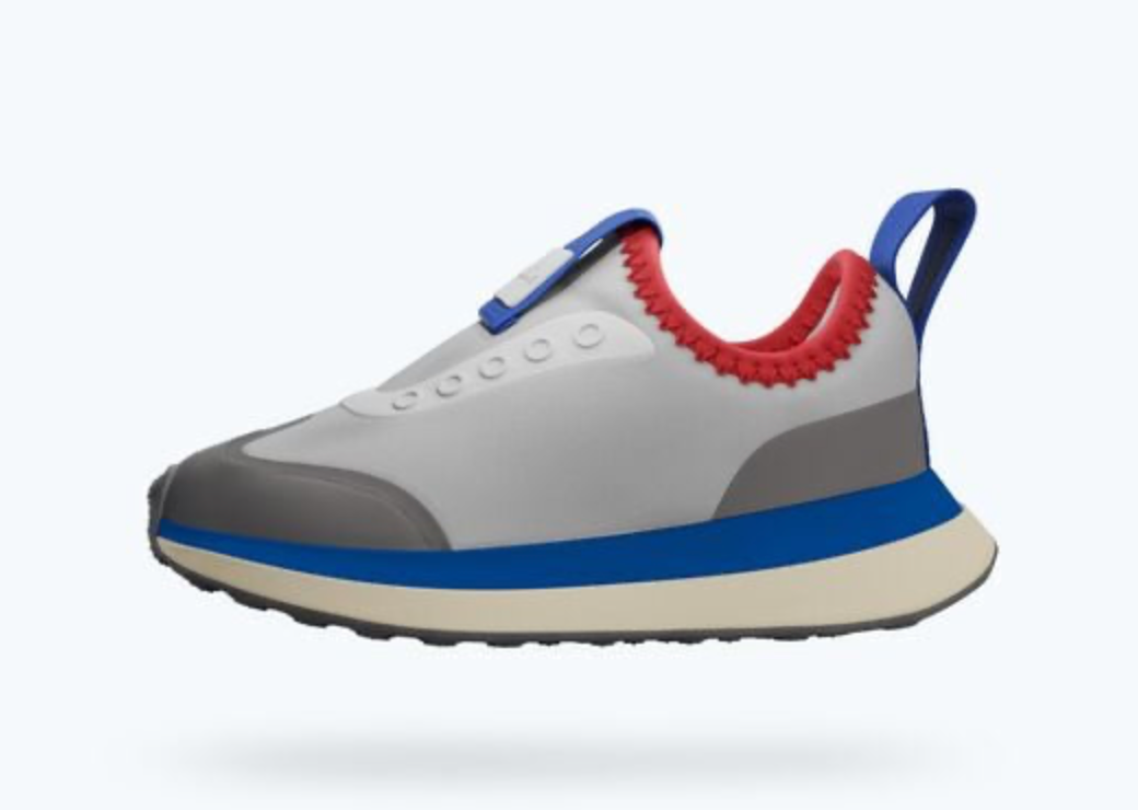 A children's slip-on sneaker in white, gray, and blue with a red collar lining, shown from a side profile on a light gray background.