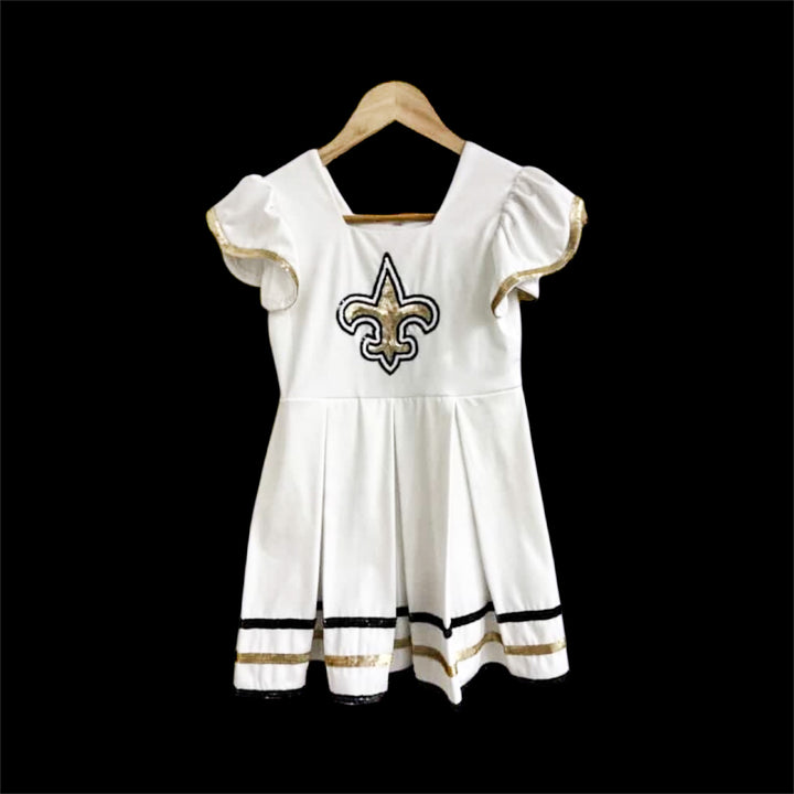 white dress with black and gold sequin fleur de lis in the center of the dress. New Orleans Saints Theme