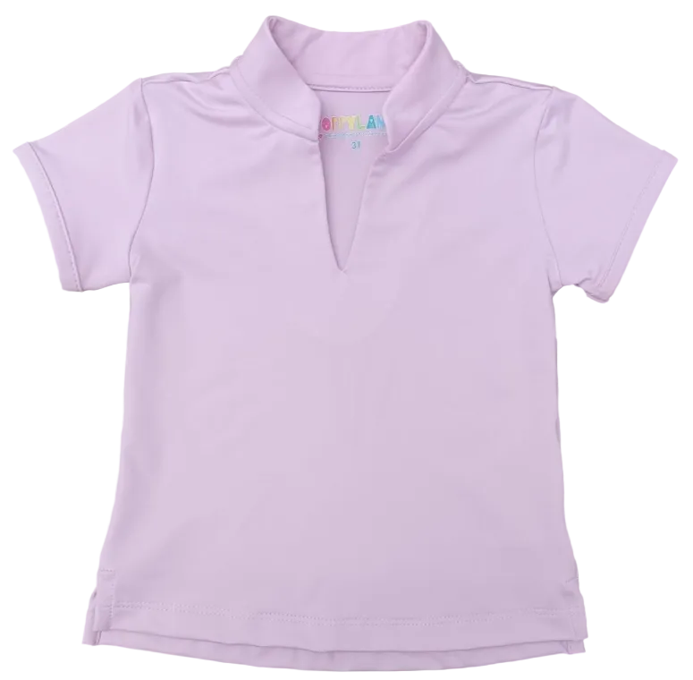 A light pink short-sleeve polo shirt with a split V-neck collar, laid flat on a gray wood-grain surface. The inside collar features a small colorful 'BOMBER' brand label.