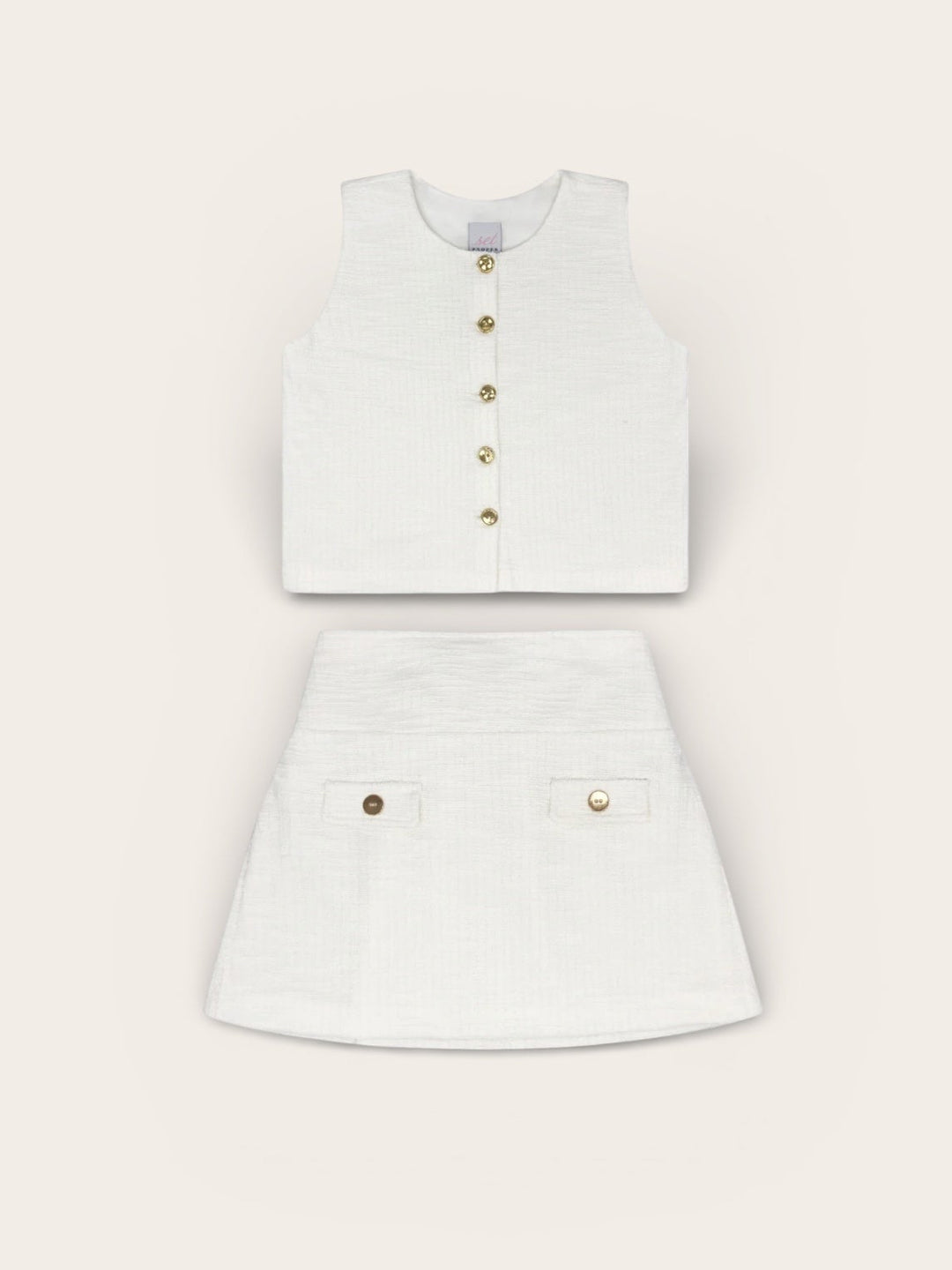 White sleeveless top and skirt set with gold buttons on a light gray background