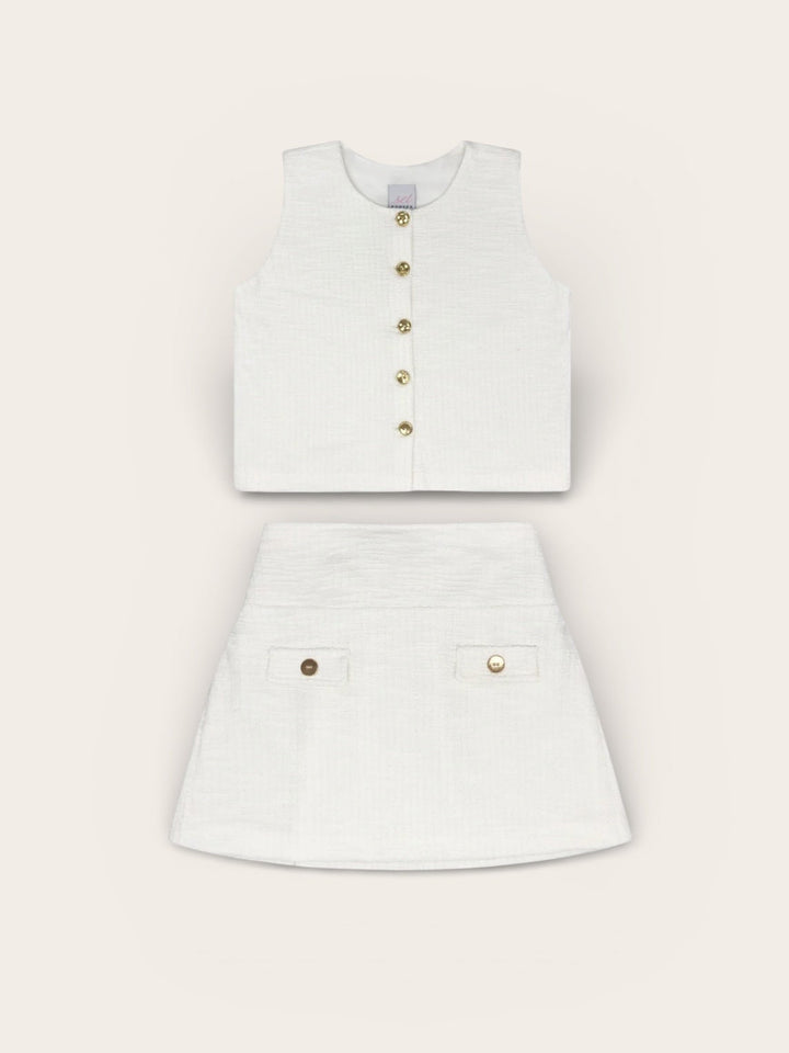 White sleeveless top and skirt set with gold buttons on a light gray background