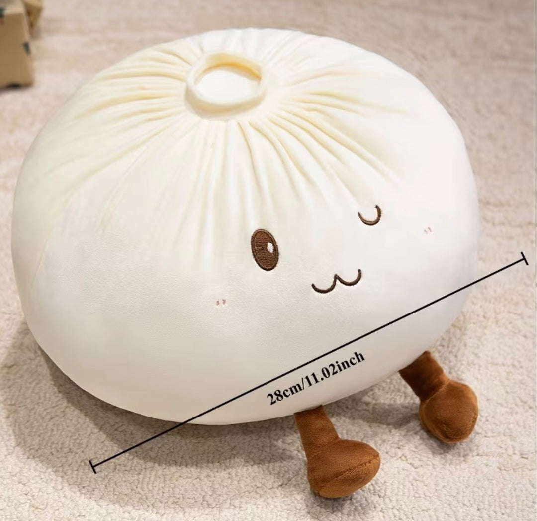 A plush bunsan-style pillow in off-white with embroidered brown facial features and small brown legs, shown on a beige carpet with a black measurement line and text indicating 28cm/11.02 inches.
