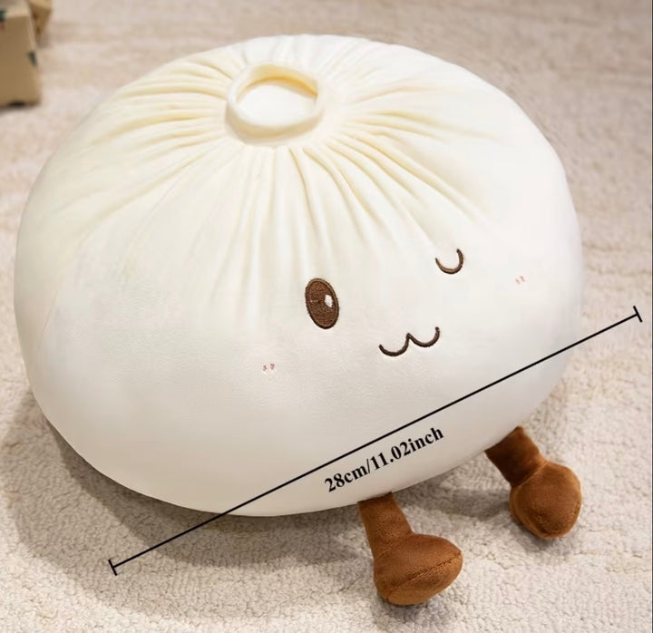 A plush bunsan-style pillow in off-white with embroidered brown facial features and small brown legs, shown on a beige carpet with a black measurement line and text indicating 28cm/11.02 inches.