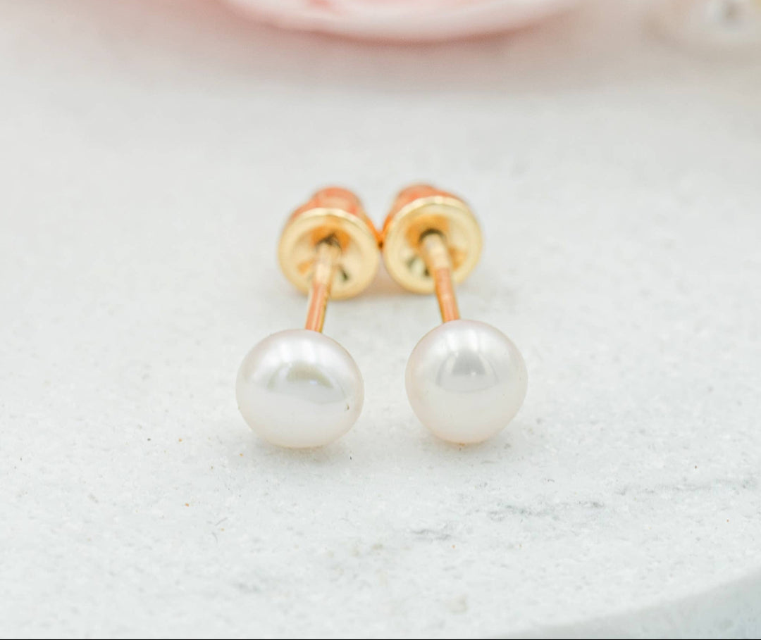 Pearl earrings with gold posts on a light background