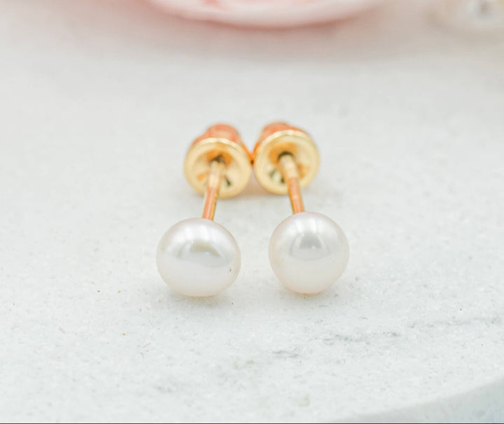 Pearl earrings with gold posts on a light background