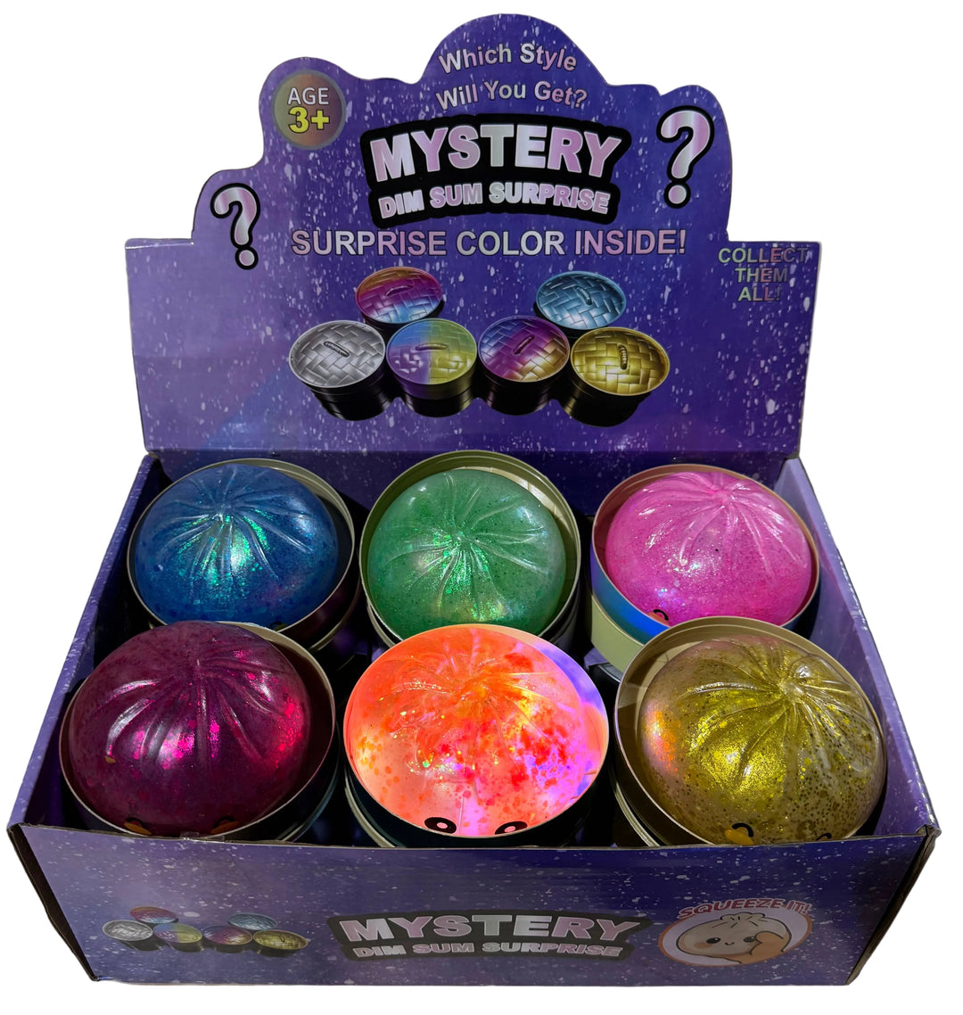A retail display box containing six small round mystery bins in different iridescent colors, with a purple branded header card reading 'Mystery Bin Bin Surprise!'.