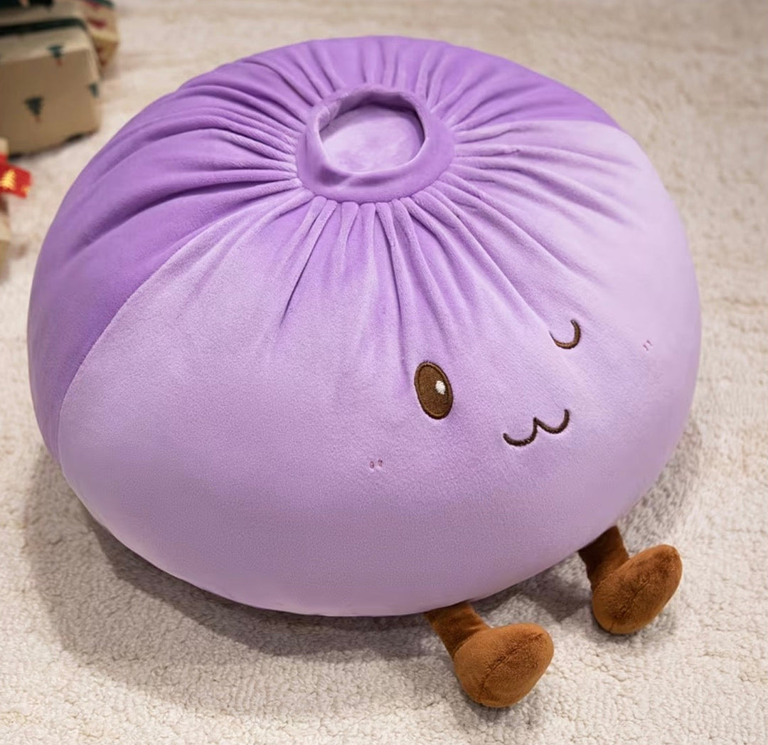 A round, plush purple dumpling or pouf with embroidered facial features and small brown legs, photographed on a light carpet.