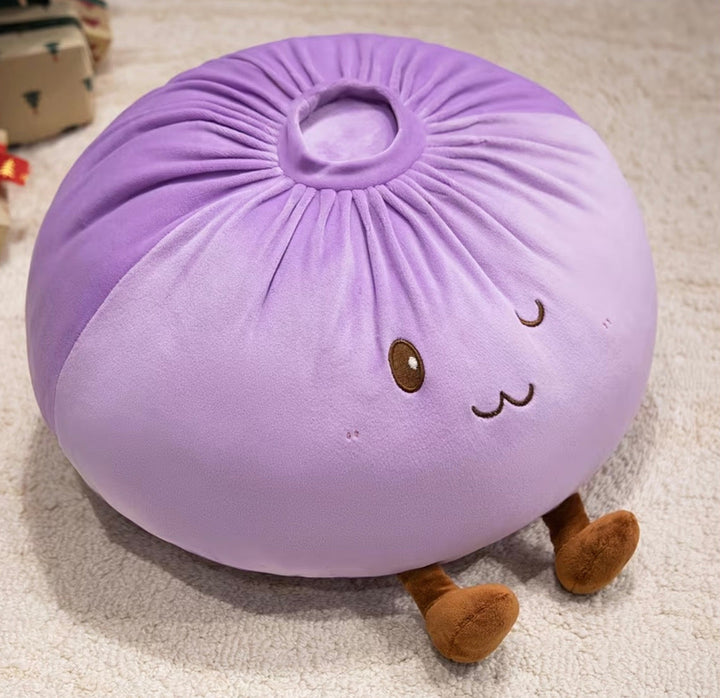 A round, plush purple dumpling or pouf with embroidered facial features and small brown legs, photographed on a light carpet.