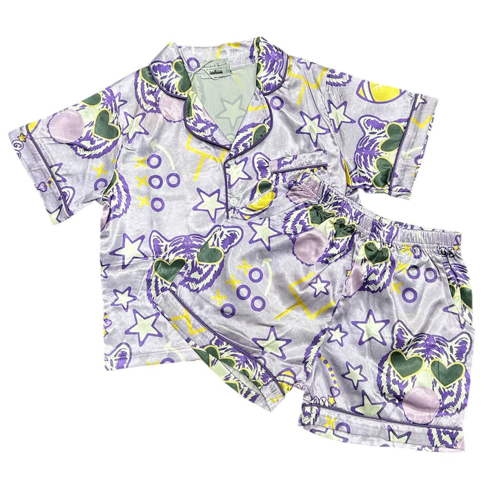 A two-piece baby pajama set featuring a short-sleeve top and matching shorts in a light gray fabric with a colorful cartoon print of purple lions, stars, and crescent moons.